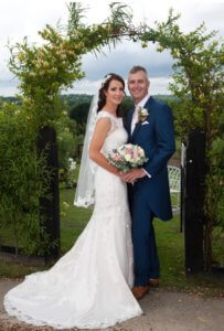 Bride and groom outside under arch. 